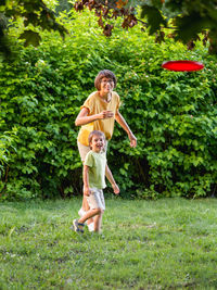 Mother and son play frisbee on grass lawn. summer vibes. outdoor leisure activity. 