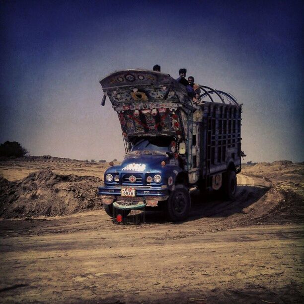 transportation, land vehicle, mode of transport, car, sky, travel, clear sky, outdoors, built structure, building exterior, architecture, day, sand, road, sunlight, incidental people, men, on the move