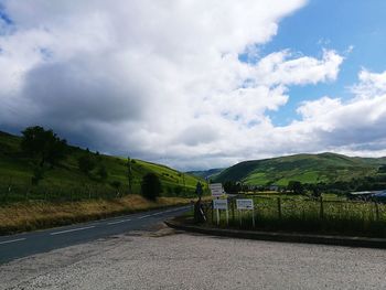 Road by mountains against cloudy sky