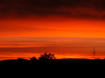 Silhouette of trees against dramatic sky during sunset