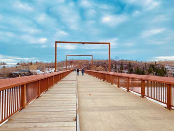 Rear view of man on footbridge against sky