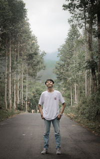 Full length portrait of man standing on road in forest
