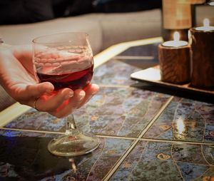 Close-up of hand holding wine glass on table