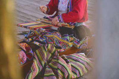 Indigenous woman showing traditional weaving technique and textile making in the andes mountain 