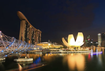 Illuminated city by river at night