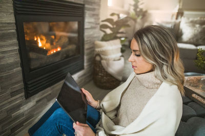 Midsection of woman sitting on sofa at home