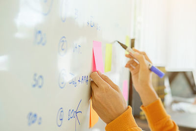 Close-up of woman writing on whiteboard