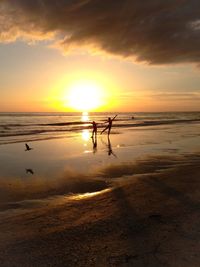 Silhouette people enjoying at beach against sky during sunset