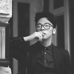 Portrait of young man with eyeglasses standing by architectural column