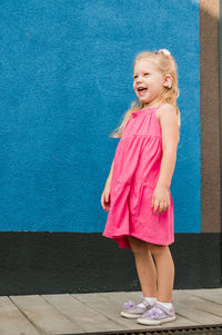 Portrait of girl standing against wall