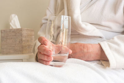 Midsection of woman sitting on bed