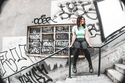 Portrait of woman standing against graffiti wall