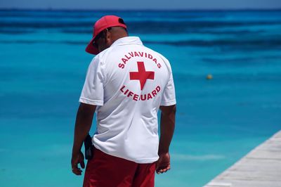 Rear view of lifeguard standing by sea