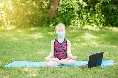 Girl child in face mask doing sport workout outdoor online. video yoga on internet. social distance 
