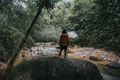 Rear view of man walking on rocks in forest