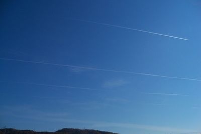 Low angle view of vapor trail against blue sky