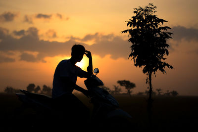 Silhouette man on field against sky during sunset