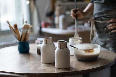 Crop photo of master leaving clay vases to dry out on round table in shop closeup