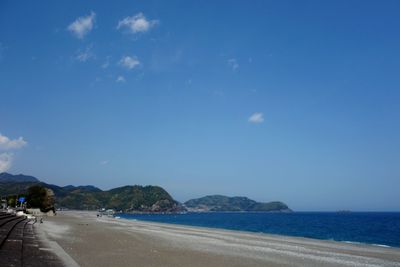 Road by sea against blue sky