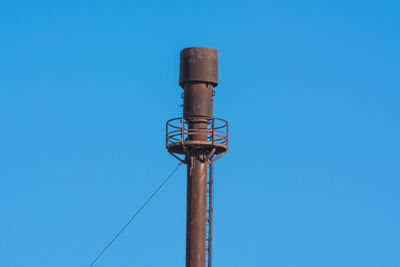 Low angle view of telephone pole against clear blue sky