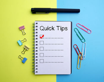 High angle view of checklist with colorful paper clips and pen on table