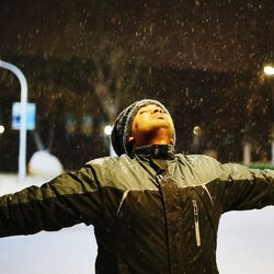 Man with arms outstretched standing during winter at night
