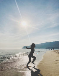 Side view of woman on beach against sky