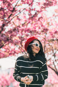 Low angle view of young woman standing against trees