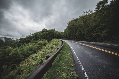 Road amidst trees against sky