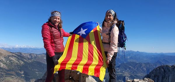 People standing on mountain against clear blue sky