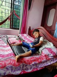 Full length of girl sitting on bed at home
