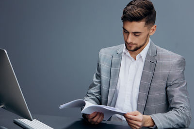 Young man using laptop while standing against blue background