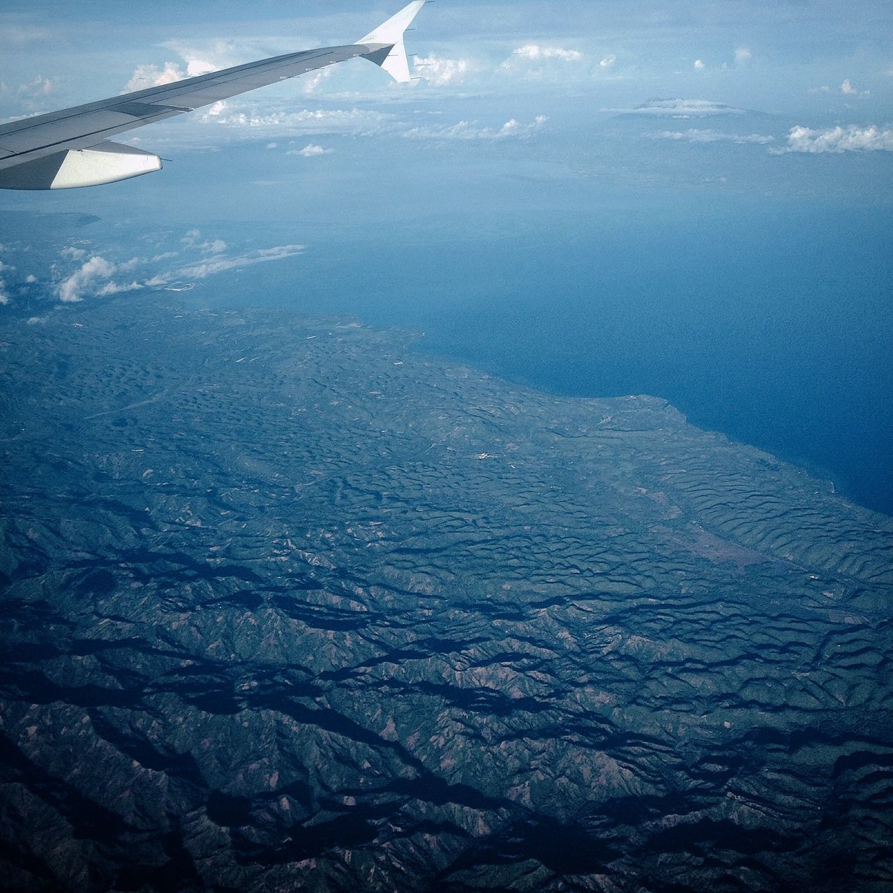 aerial view, flying, transportation, mountain, airplane, scenics, aircraft wing, mode of transport, beauty in nature, tranquil scene, air vehicle, landscape, tranquility, nature, water, mountain range, sea, travel, part of, blue