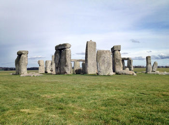 Old ruins on grassy field against cloudy sky