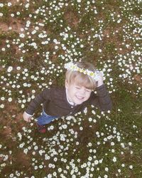 High angle view of cute boy wearing flowers while standing on grass