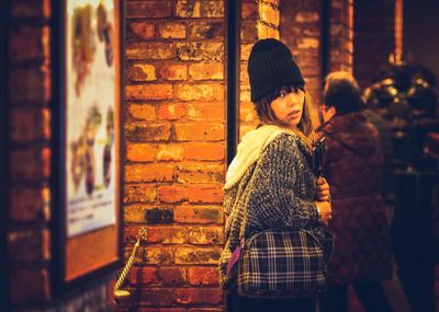 Woman standing against illuminated wall during winter