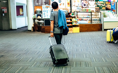 Rear view of young man walking on tiled floor