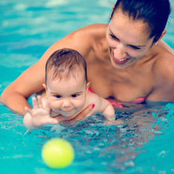 Mother sitting with toddler son in pool