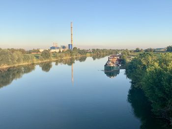View of factory by river against sky