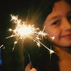 Close-up of girl holding sparkler at night