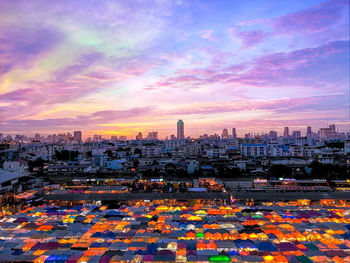 High angle view of illuminated market in city against cloudy sky