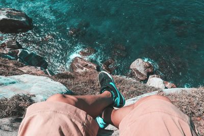 High angle view of man sitting on mountain against sea