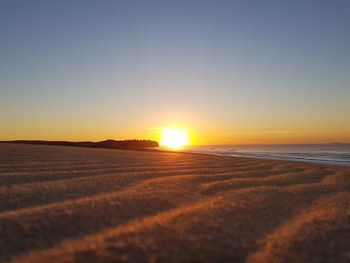 Scenic view of beach against clear sky during sunset