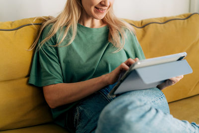 Midsection of woman using mobile phone while sitting on sofa at home