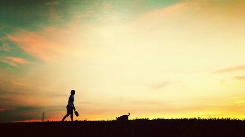 Silhouette of people standing on field at sunset