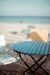 Chairs on sand at beach against sky