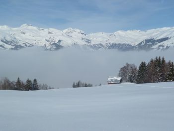 Snow covered road by mountains against sky