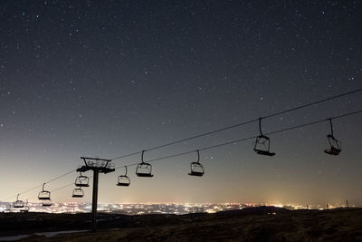 Low angle view of overhead cable car against sky at night