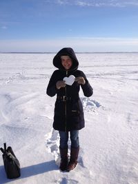 Full length portrait of young woman holding shape on snow covered landscape