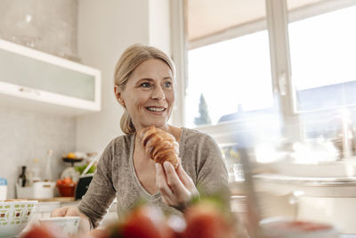 Woman at home eating a croissant